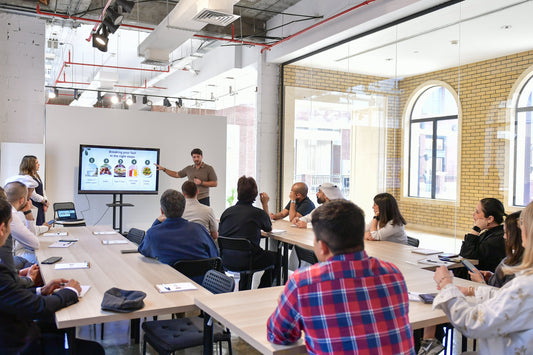 Group of people in a modern office setting with a presentation on a screen.